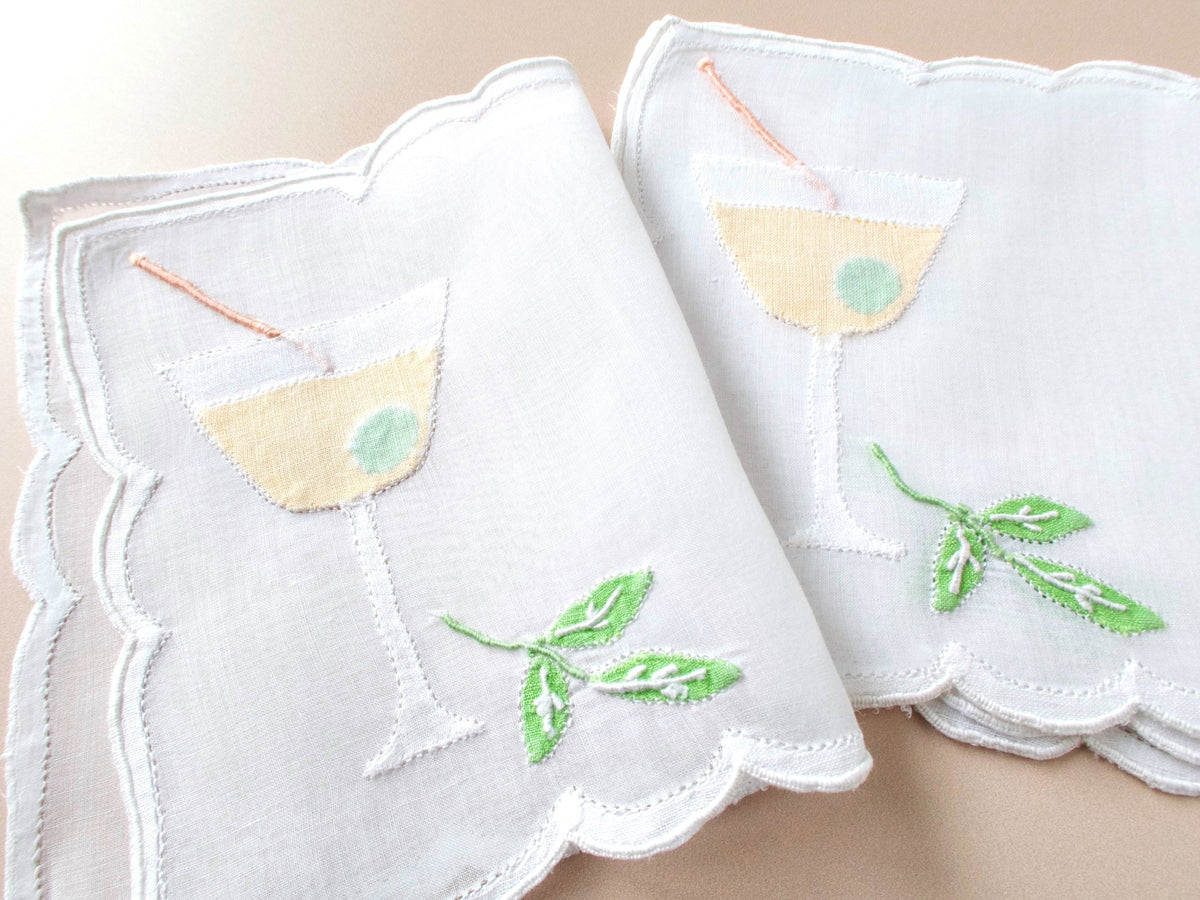 Fanned set of vintage Madeira organdy cocktail napkins showing full martini glass design with shadow appliqué olive and embroidered cocktail pick.