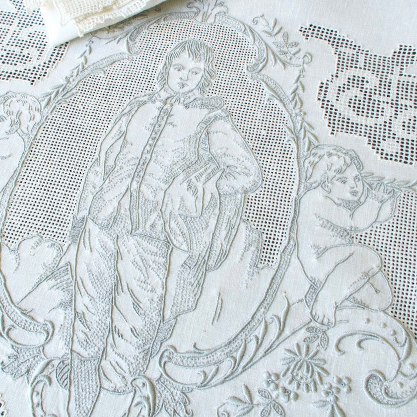 vintage decorative embroidered tablecloth with intricate patterns and a the famous Blue Boy, along with a cherub