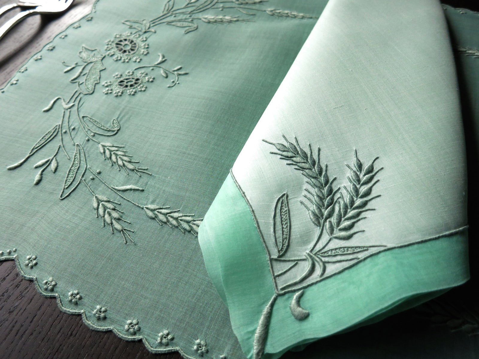 Close-up of green Marghab Wheat embroidered linen napkin, Madeira handwork detail.
