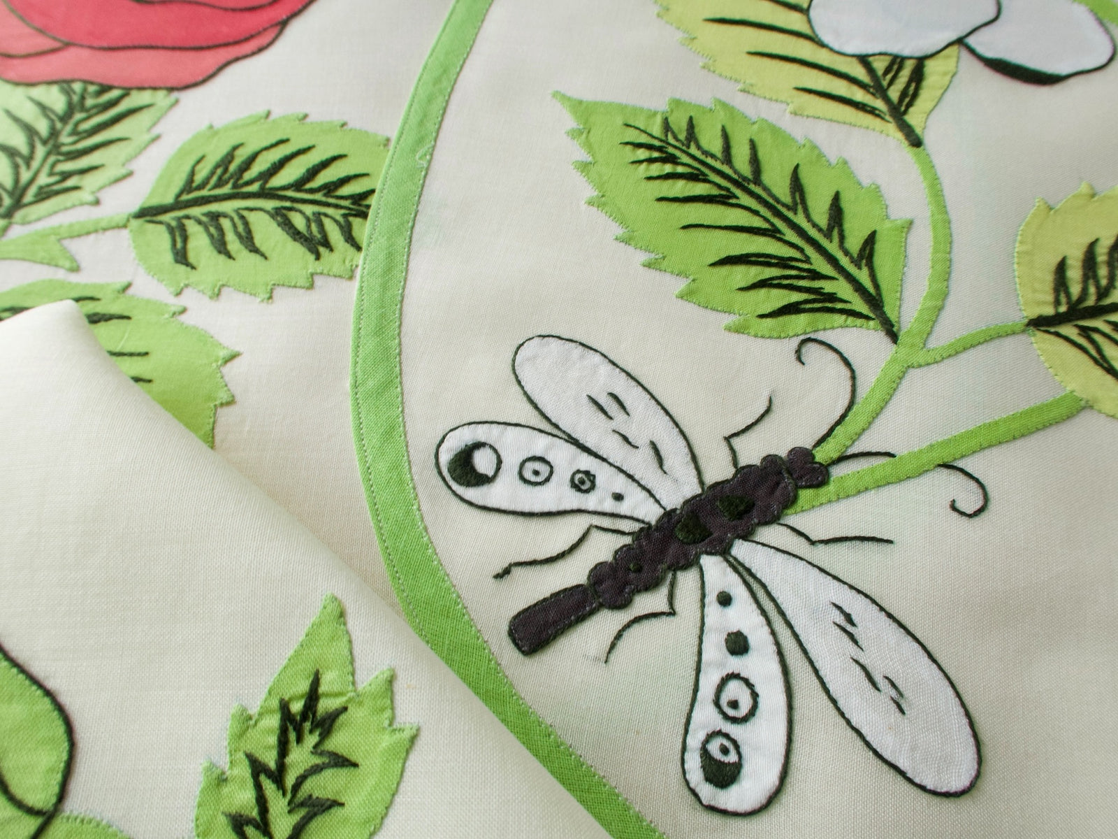 Vintage Italian appliqué placemats fanned out showing dragonfly, roses in white and red, green border on semi-sheer linen