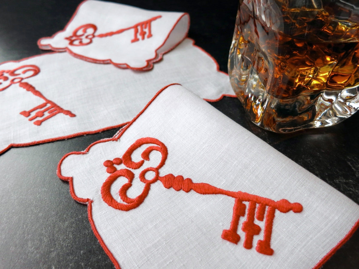 Vintage Madeira cocktail napkins with red skeleton key embroidery, styled with whiskey glass on dark surface