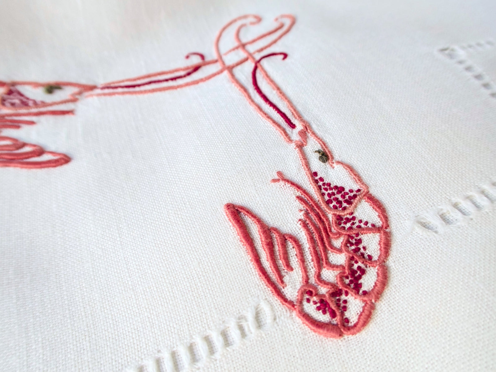 Detail of single langoustine embroidery on antique French linen, showing three-dimensional stitchwork