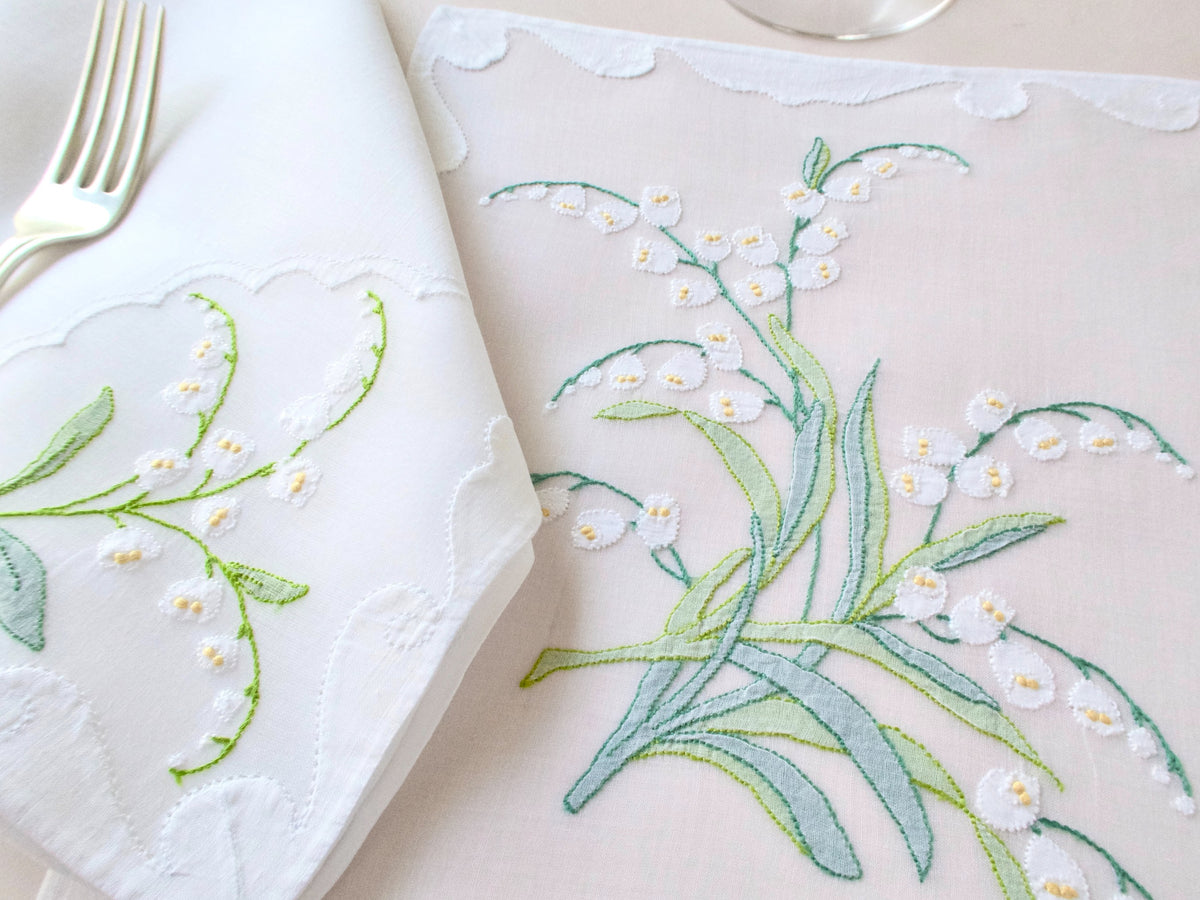Detail of cascading Lily of the Valley embroidery with raised white blossoms and yellow centers on vintage organdy placemat.