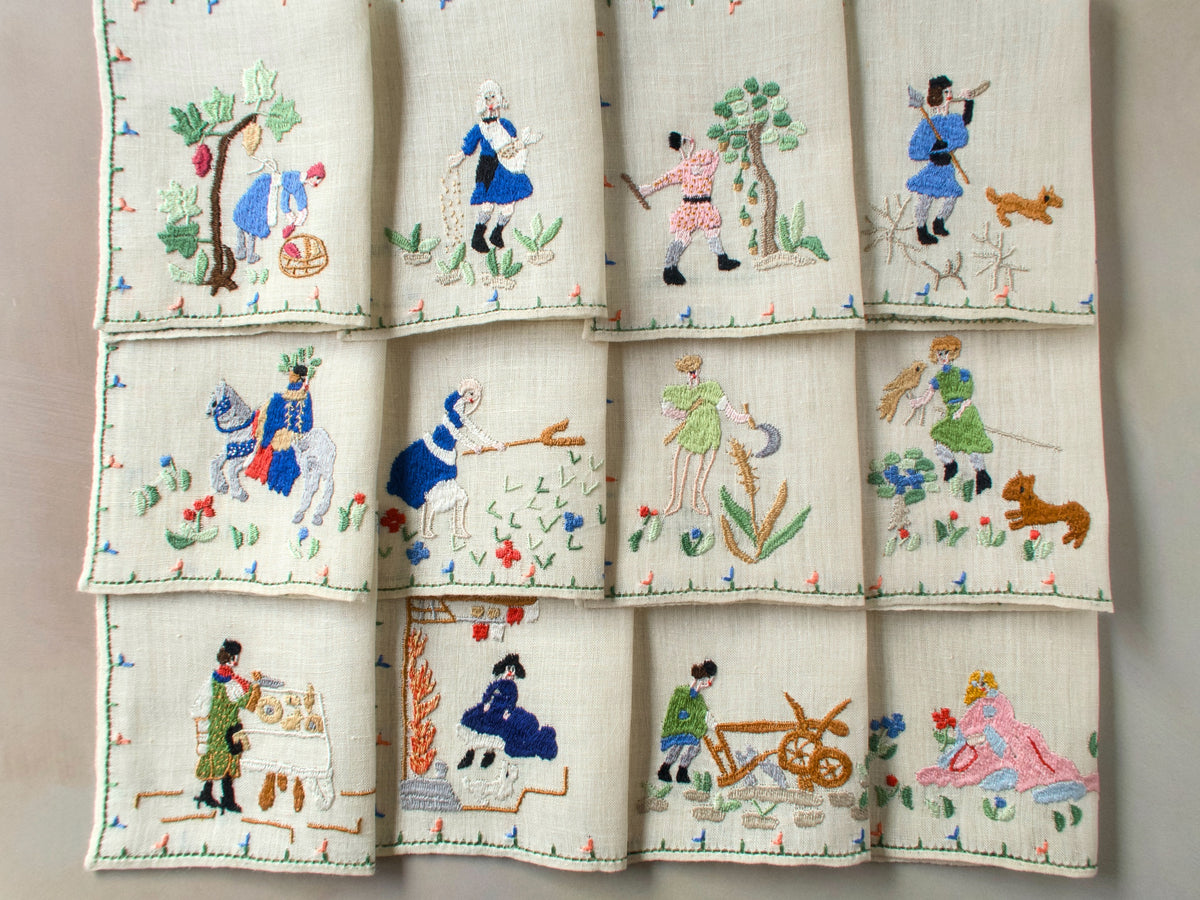Full set of twelve Months of the Year Rapisardi napkins arranged in three rows, each showing a different monthly scene with figures and flowers.