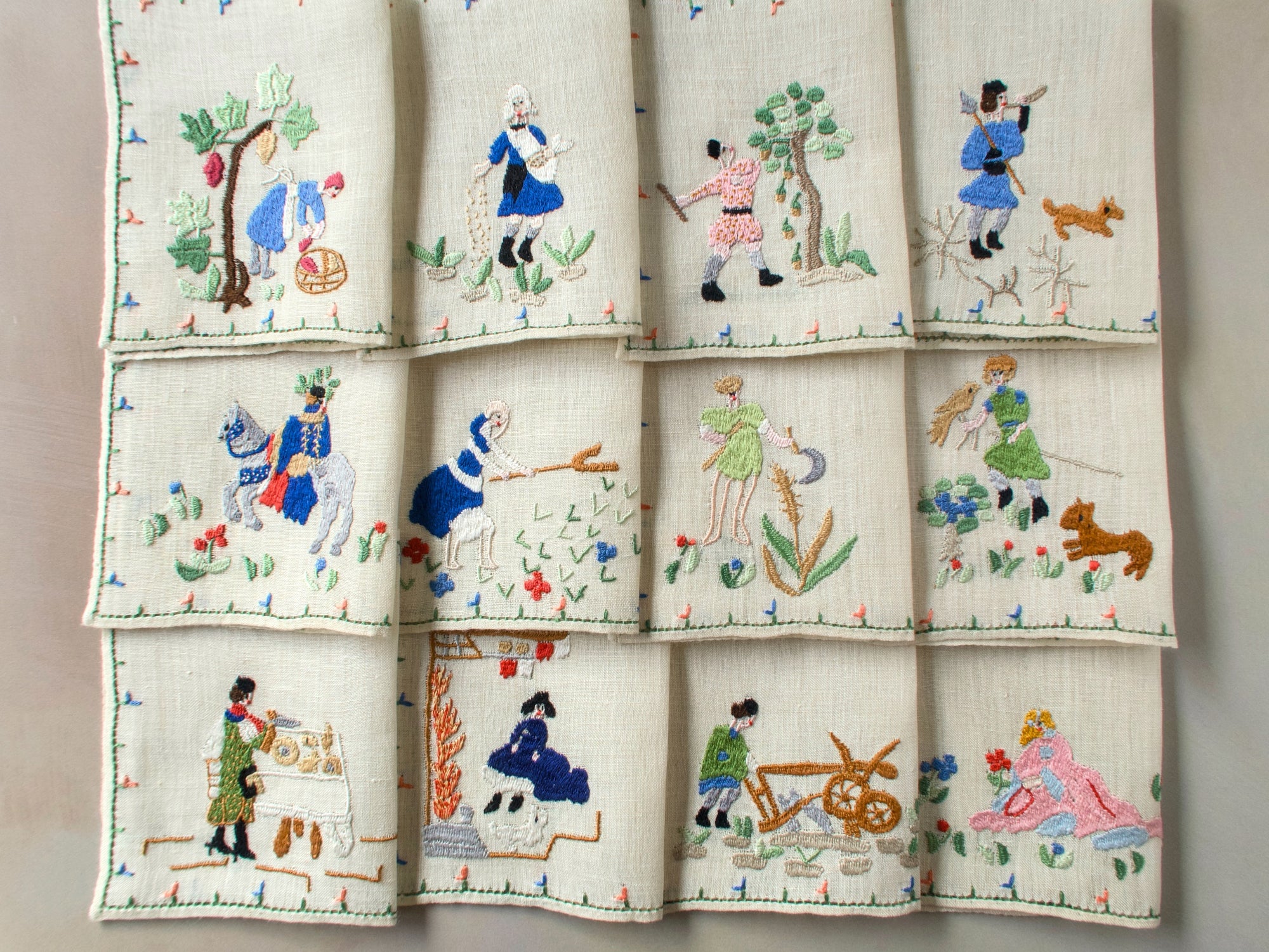 Full set of twelve Months of the Year Rapisardi napkins arranged in three rows, each showing a different monthly scene with figures and flowers.