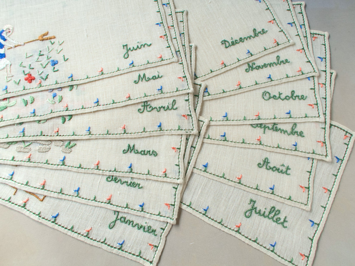 Stacked set of Rapisardi months napkins showing each month’s name embroidered in French on the border.