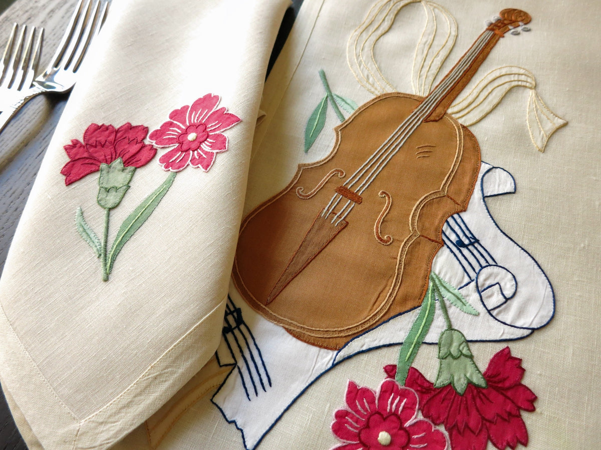 Detailed view of a vintage Italian embroidered placemat with a musical instrument and flowers.