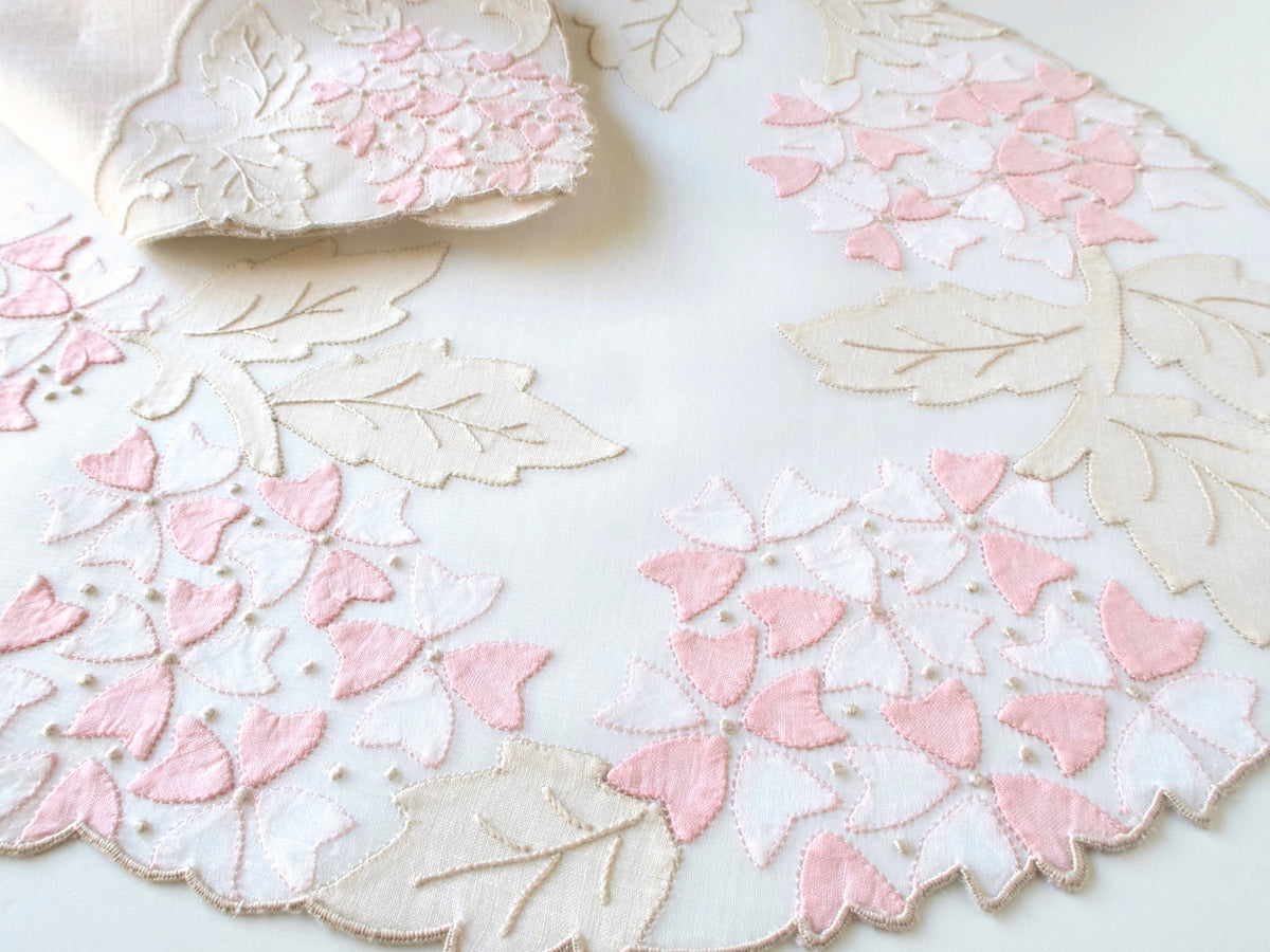 Vintage Madeira organdy placemat with pale pink viburnum appliqué and hand embroidered flowers and ecru leaves on sheer ground, scalloped edge, white background.