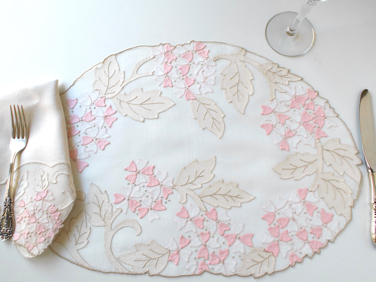 Vintage Madeira organdy placemat set for 8 with folded napkin and fork showing place setting scale and pink viburnum embroidery detail.