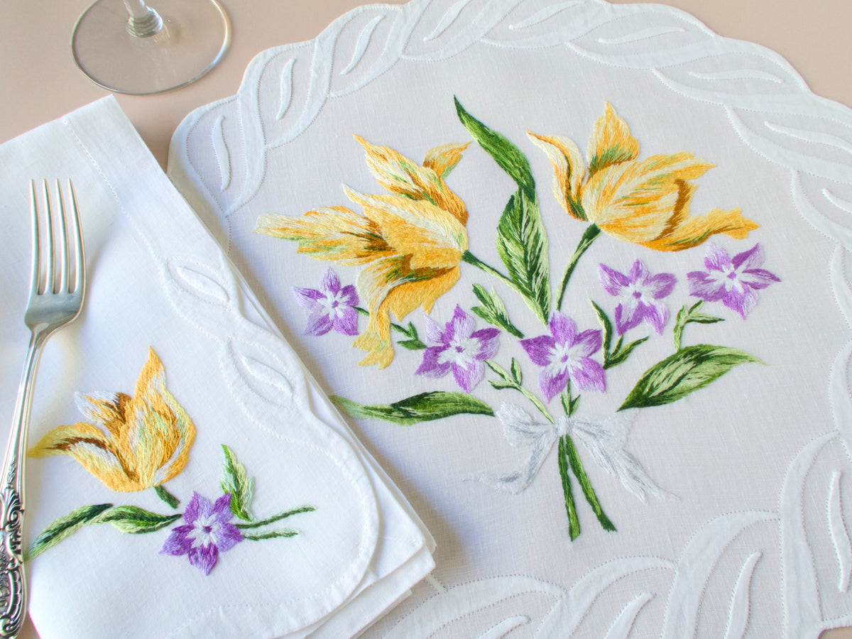 D. Porthault vintage French linen placemat and napkin showing yellow tulips and purple bellflowers, with scalloped embroidered borders.