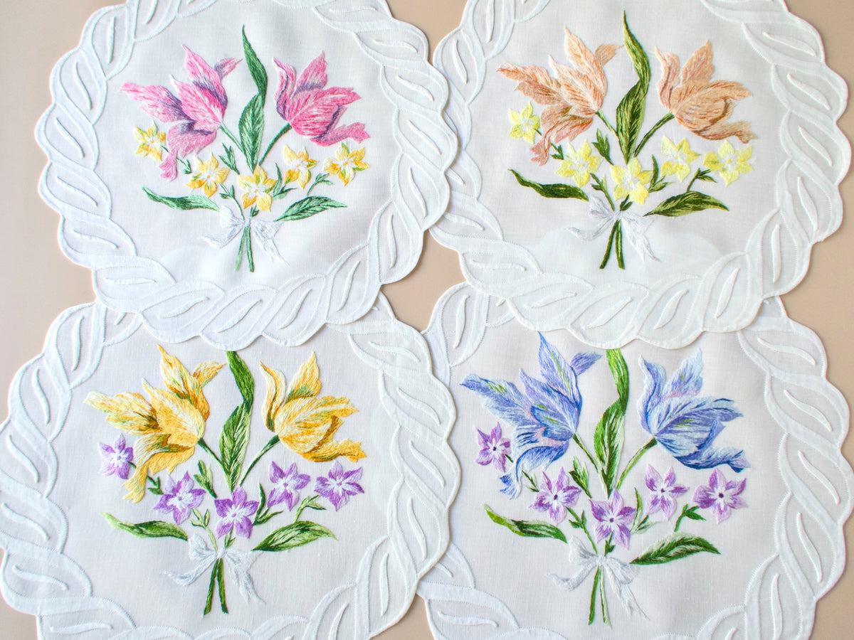 Round scalloped D. Porthault vintage linen placemat embroidered with yellow tulips, blue tulips, and mixed wildflower bouquets.