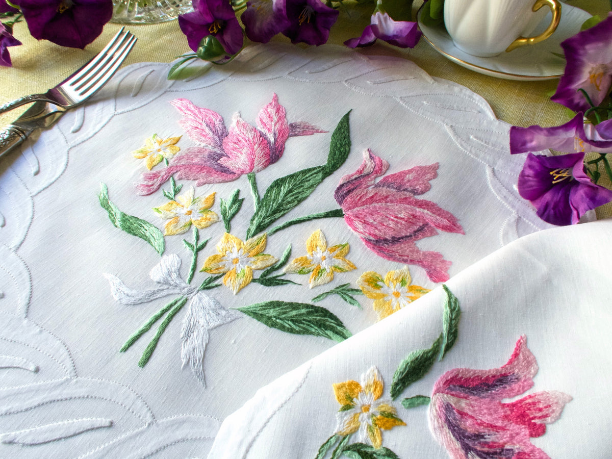 Vintage D. Porthault French linen napkin hand embroidered with pink tulips, yellow wildflowers, and green leaves.