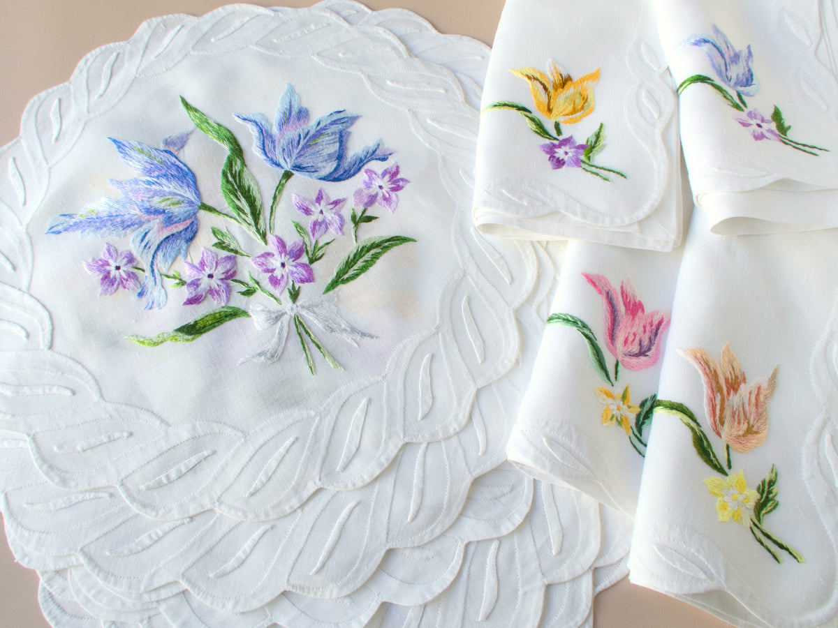 Vintage D. Porthault hand embroidered linen showing blue and purple tulips with pink flower accents, from a 24-piece set for 12.