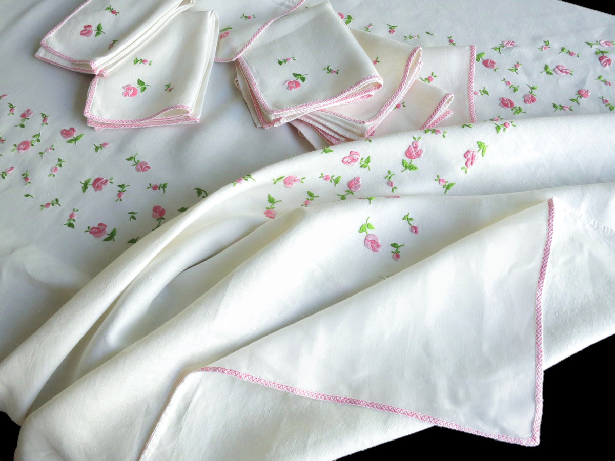 Stack of vintage European linen napkins hand embroidered with scattered rosebuds and pale pink monogram, showing continental sizing​​​​​​​​​​​​​​​​