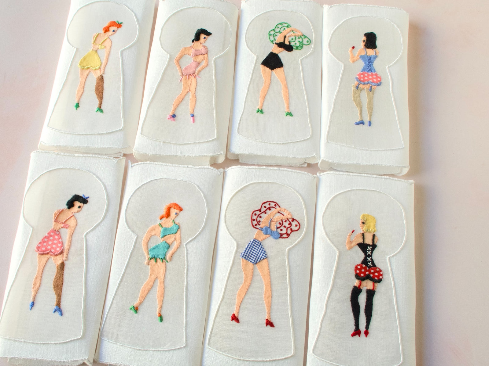 Set of eight vintage Madeira cocktail napkins hand embroidered with playful pin-up figures seen through keyhole designs.