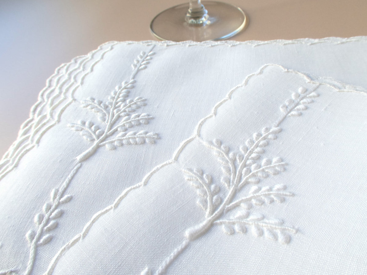 Close-up of whitework leaf embroidery on vintage Madeira linen cocktail napkin, showing fine raised stitching.