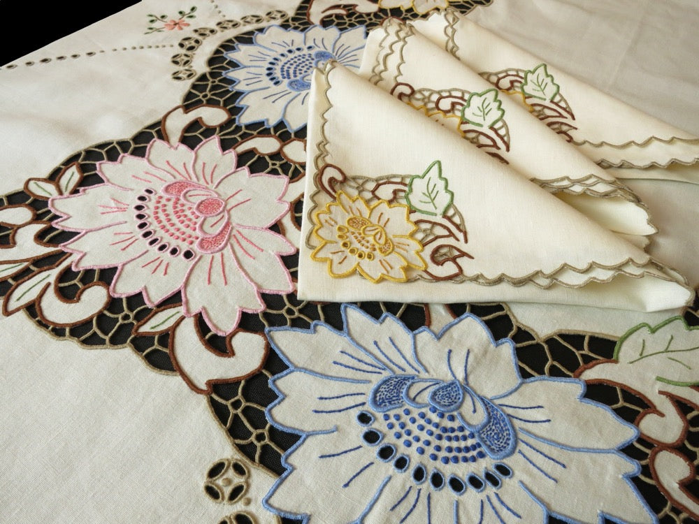 Vintage Madeira tablecloth and napkins hand embroidered with multicolored Richelieu florals on ivory linen, showing cheerful mid-century Madeira craftsmanship.